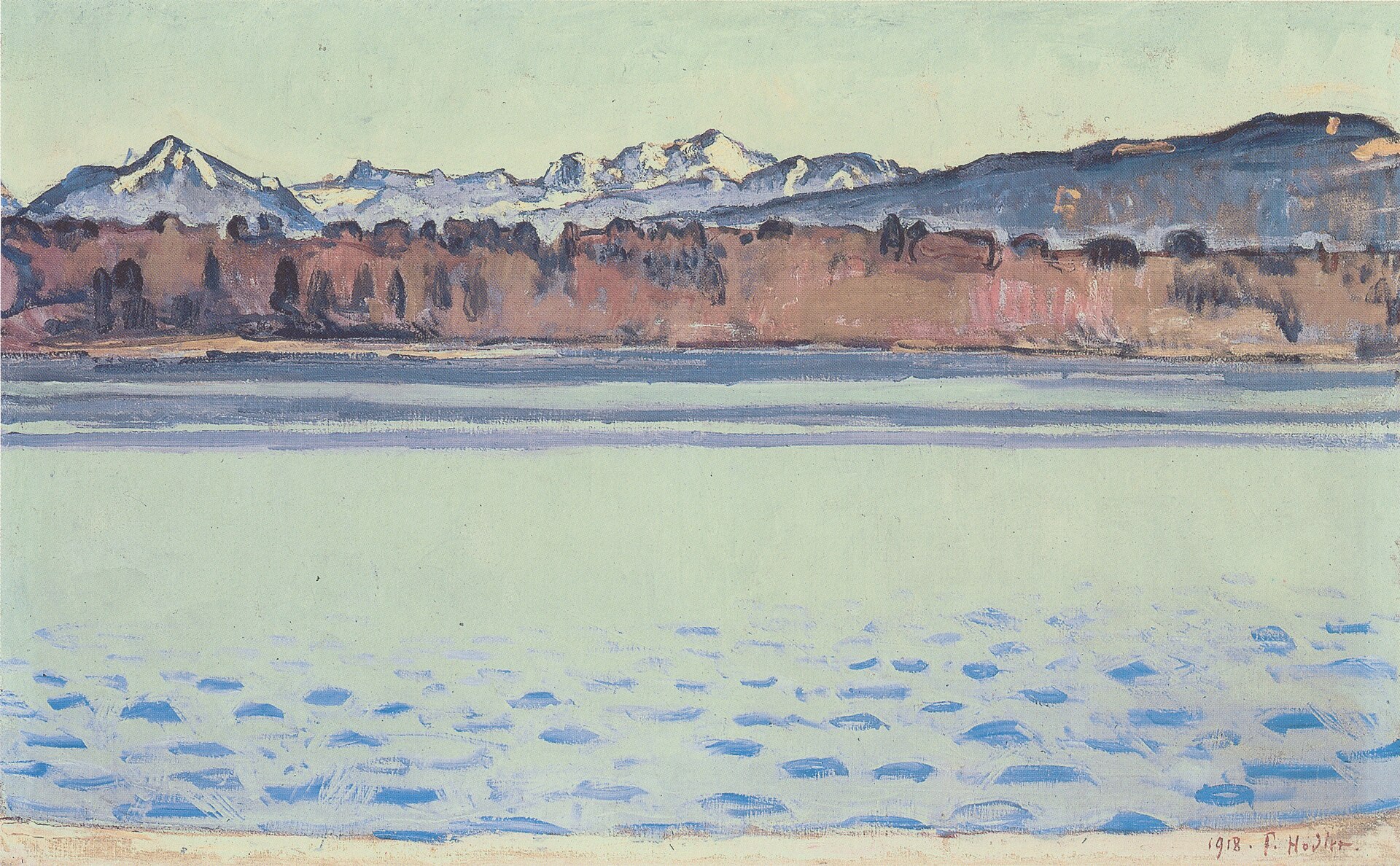 The snow-covered Mont Blanc massif rises in white peaks behind a russet wooded shore and bands of pale blue lake water.