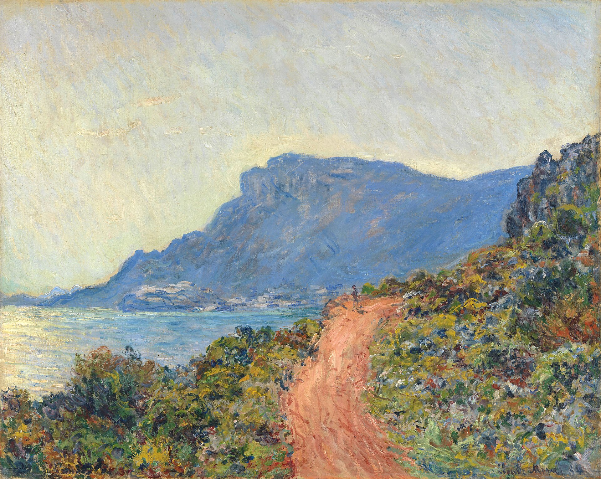 A red-ochre coastal path winds through sunlit scrub above a turquoise bay, with the blue mountain behind Monaco and the town on its low rock at the water's edge.