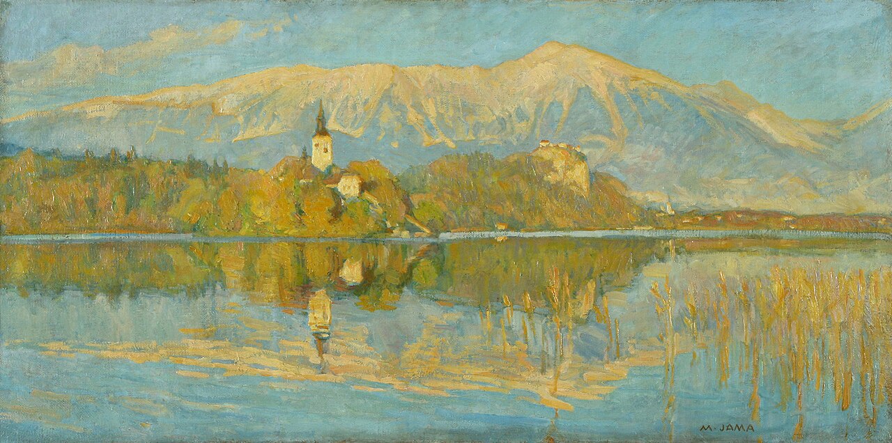 Lake Bled in golden autumn light, with the island church's white bell tower, Bled Castle on its cliff to the right, and sunlit Karavanke mountains behind, all mirrored in the still water among reeds.
