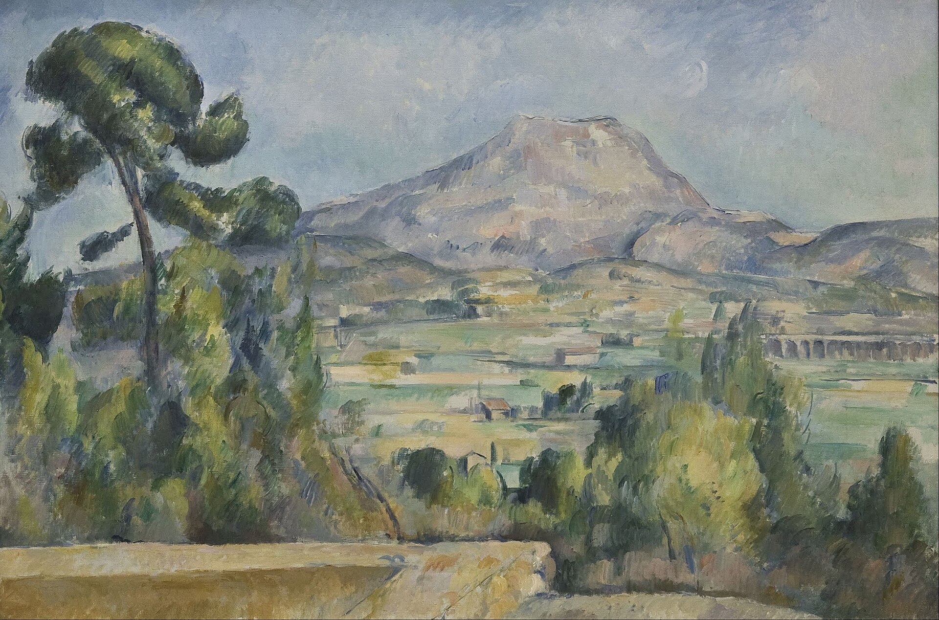 Cézanne's Mont Sainte-Victoire rises pale lilac and ochre above the green patchwork of the Arc valley near Aix, with a tall umbrella pine on the left and the railway viaduct on the right.
